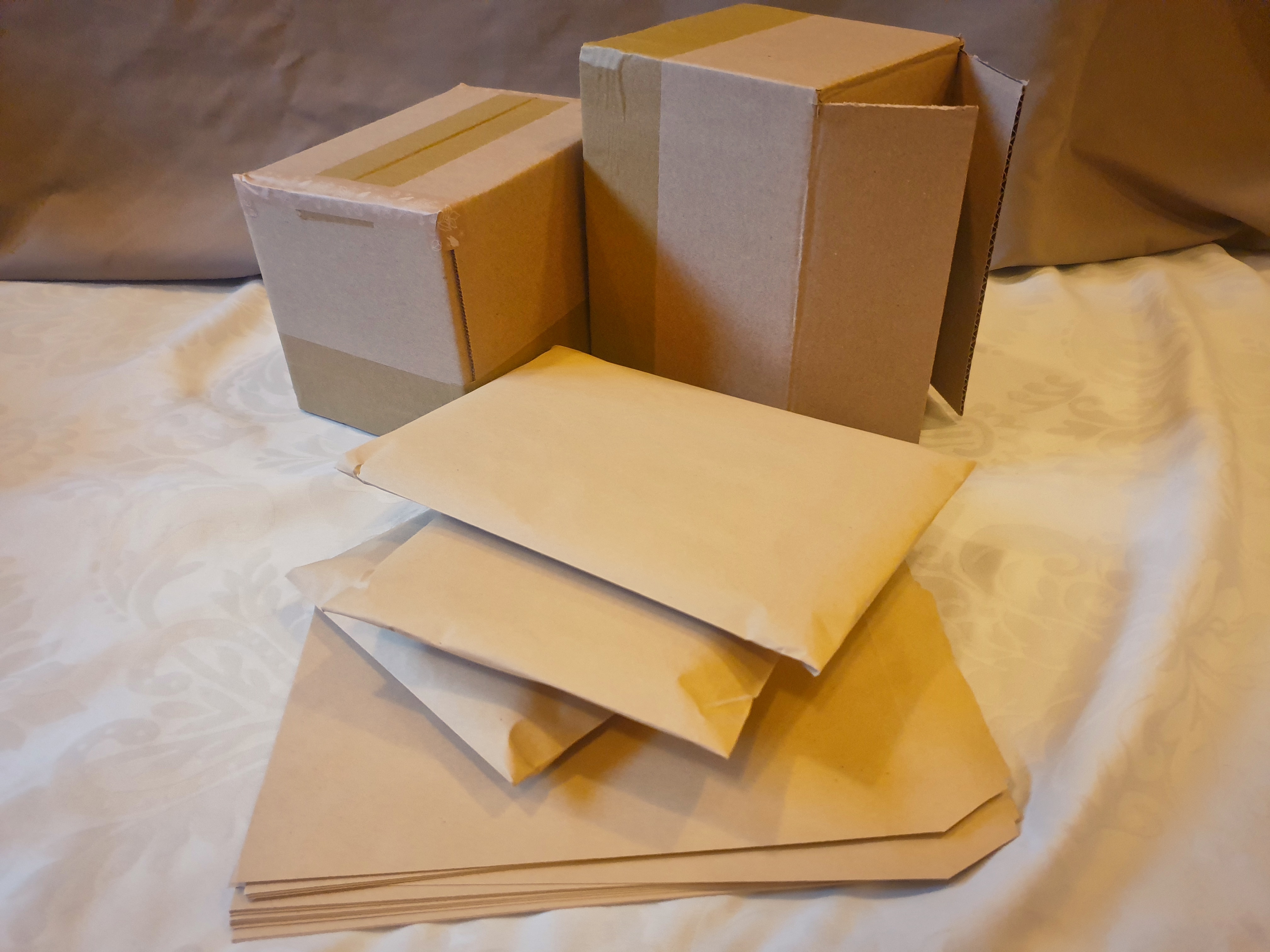 A photo of two boxes in the background, and envelopes in the foreground. Some envelopes are packed and some are unpacked