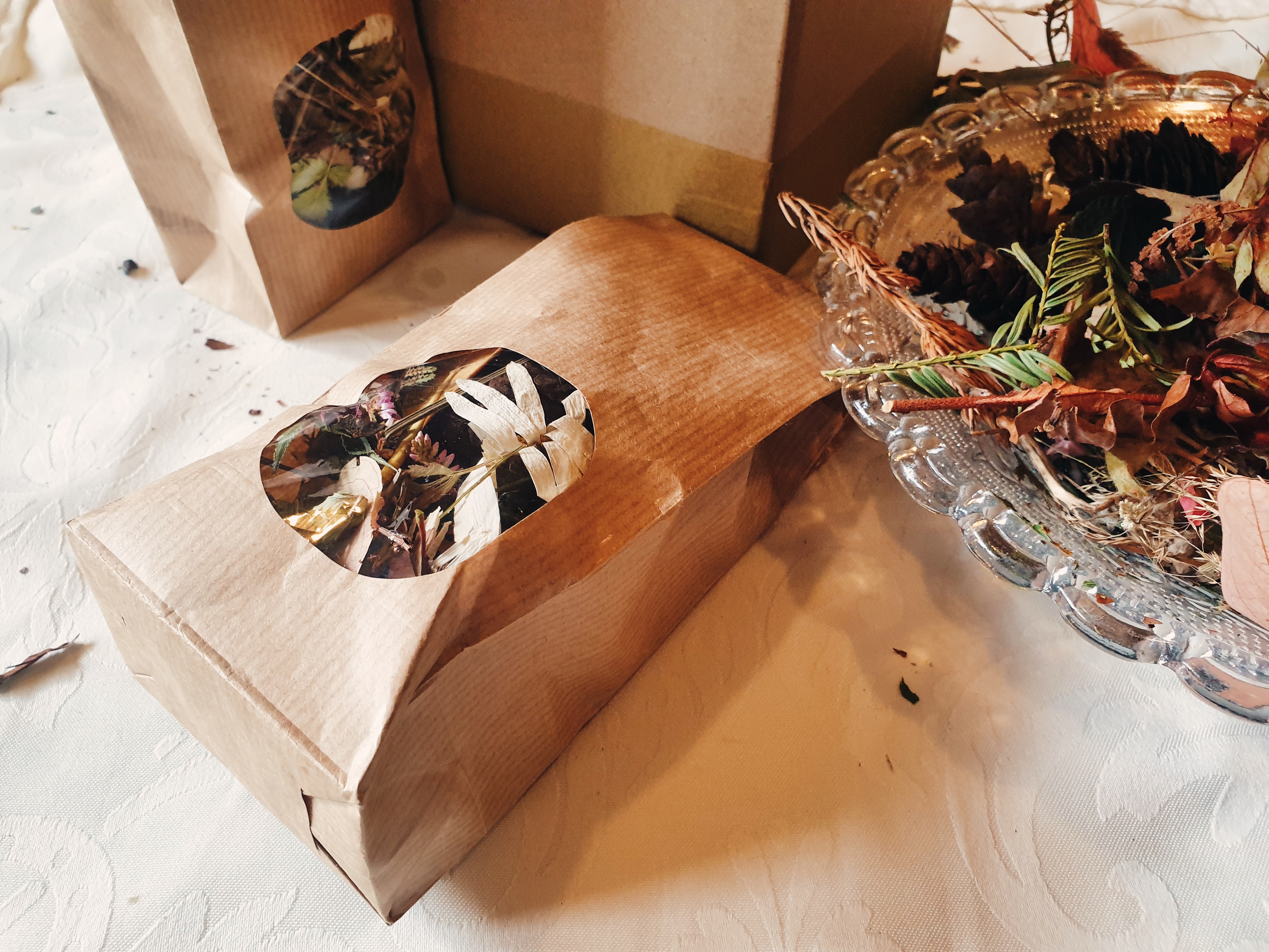 Photo featuring two bags of potpourri, as well as a box at the back, and a bowl of potpourri on the right.